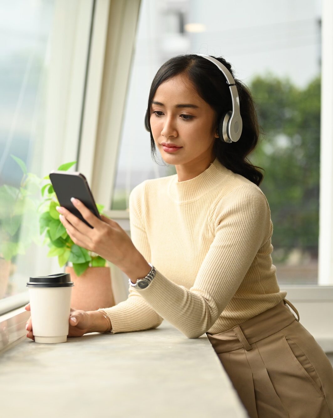 Pretty young woman in wireless headphone chatting with friends on mobile phone.